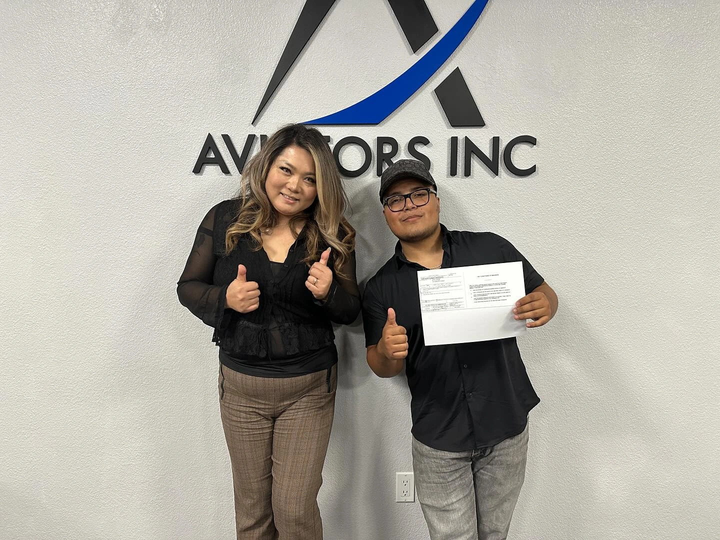 Instructor and student giving thumbs up in front of an aircraft