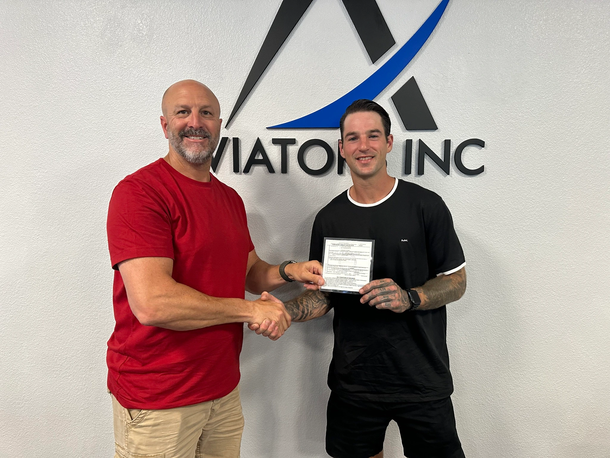 Instructor and student shaking hands in front of a training aircraft