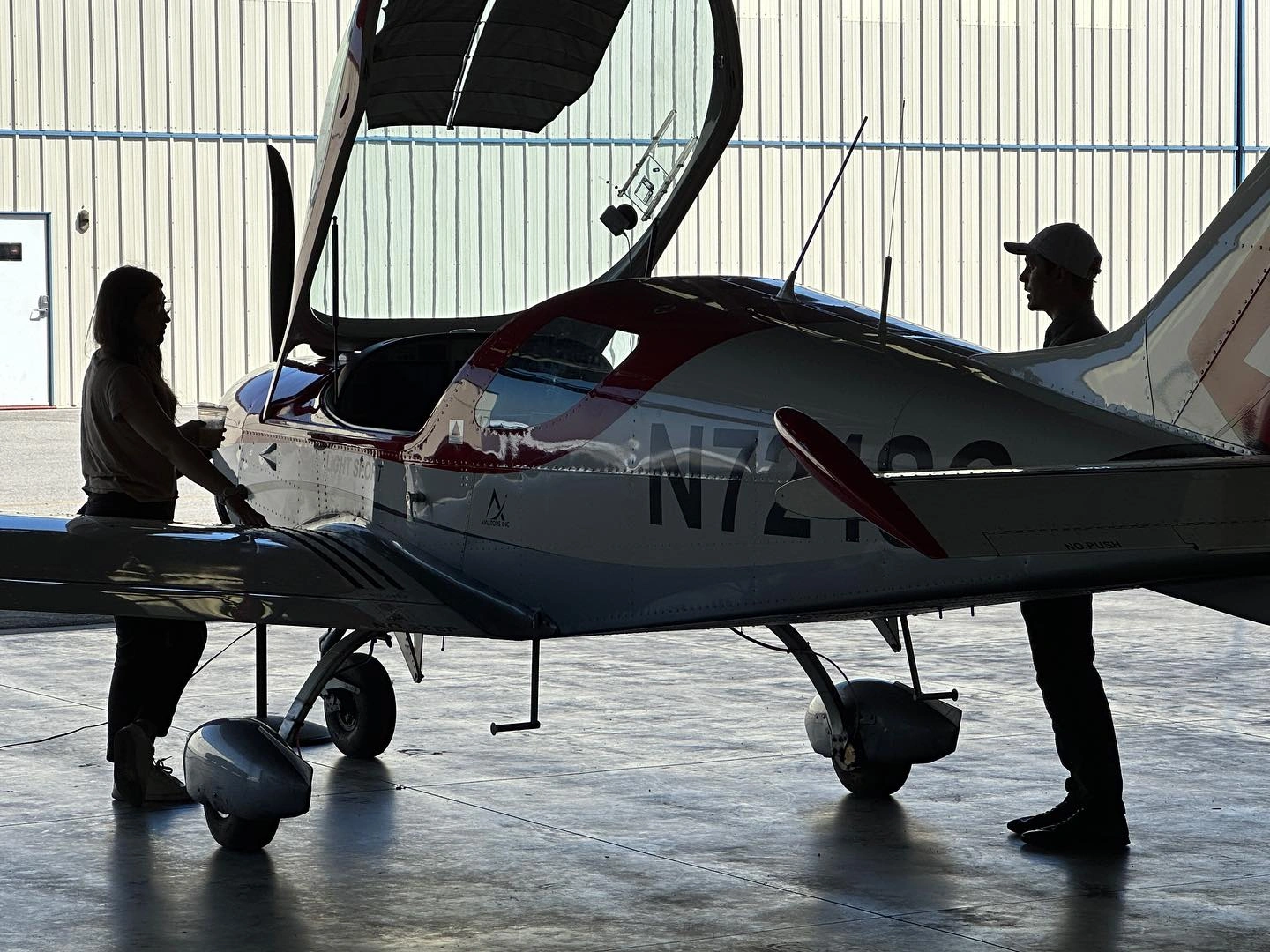 Aviators Flight Academy staff and airplane inside a well-lit hangar
