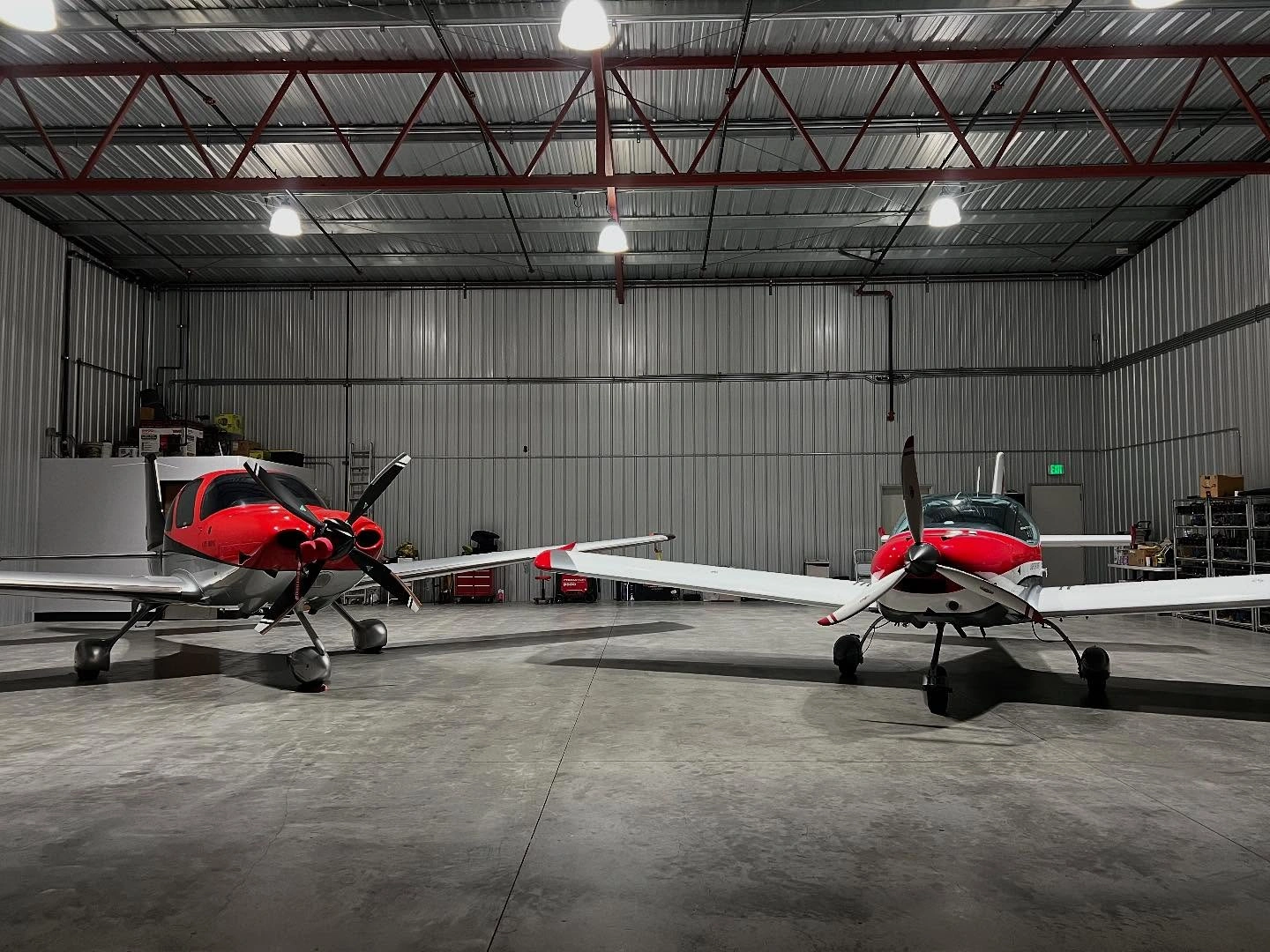 Two modern training airplanes parked perfectly inside a hangar